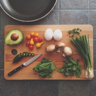 A cutting board laid out with fresh produce and a knife