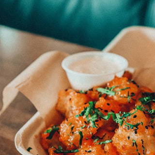 A takeaway basket of freshly fried food with a dip